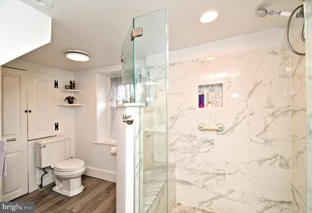 full bathroom featuring baseboards, wood finished floors, a marble finish shower, and toilet