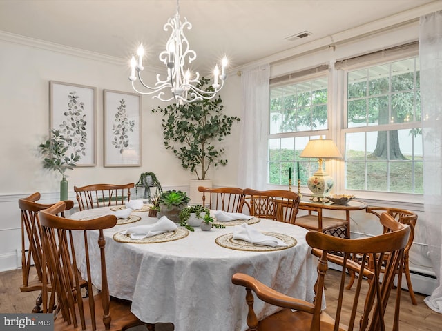 dining space featuring ornamental molding, a chandelier, wood finished floors, and visible vents