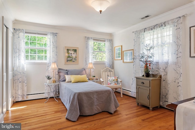 bedroom featuring visible vents, ornamental molding, light wood finished floors, and a baseboard radiator