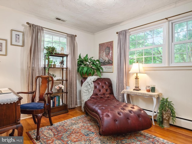 living area with visible vents, a textured ceiling, and wood finished floors
