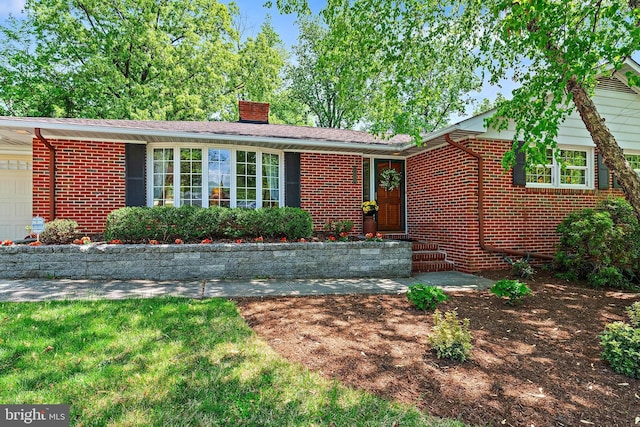 single story home featuring a garage, a chimney, and brick siding