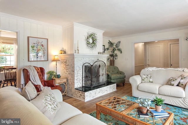 living area featuring ornamental molding, wood finished floors, and a fireplace