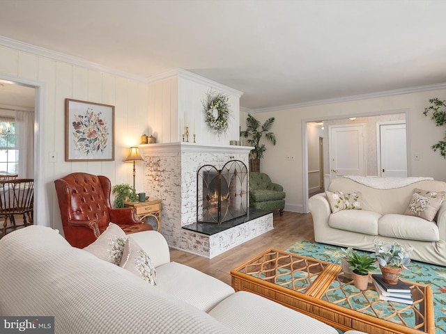 living room featuring baseboards, ornamental molding, wood finished floors, and a fireplace