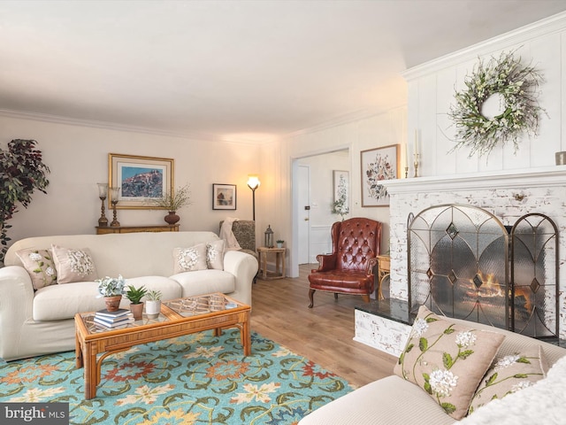 living area featuring crown molding, wood finished floors, and a fireplace