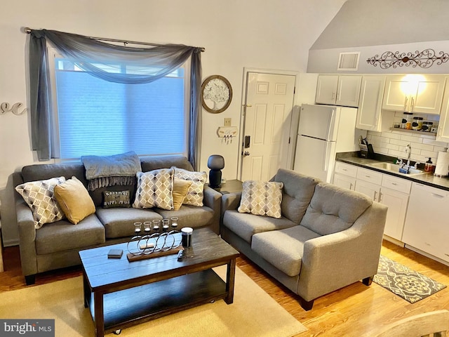 living room featuring visible vents, vaulted ceiling, and light wood-style floors