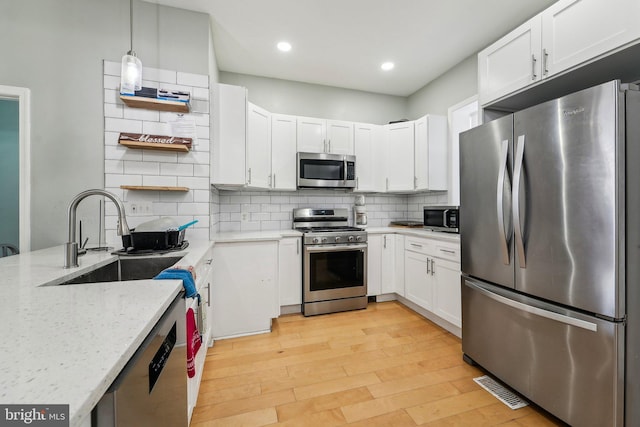2519 Reisterstown Rd, Baltimore, MD 21217 - kitchen with stainless steel appliances, open shelves, a sink, light stone counters, and light wood-style flooring
