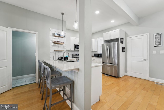 2519 Reisterstown Rd, Baltimore, MD 21217 - kitchen with appliances with stainless steel finishes, a sink, a peninsula, white cabinetry, and baseboards