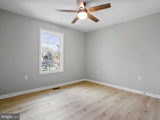 empty room with visible vents, light wood-style flooring, baseboards, and ceiling fan