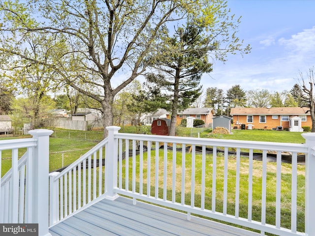 wooden terrace with fence, a storage shed, a yard, a residential view, and an outbuilding