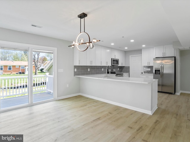 kitchen featuring decorative backsplash, a peninsula, stainless steel appliances, and light countertops