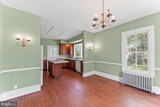 kitchen featuring radiator heating unit, white dishwasher, a center island with sink, light countertops, and dark wood-style floors