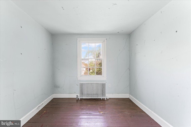 spare room with radiator heating unit, hardwood / wood-style flooring, and baseboards