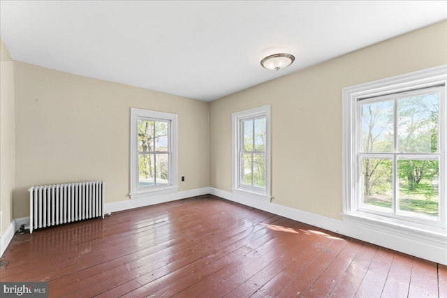 spare room featuring hardwood / wood-style floors, baseboards, a wealth of natural light, and radiator