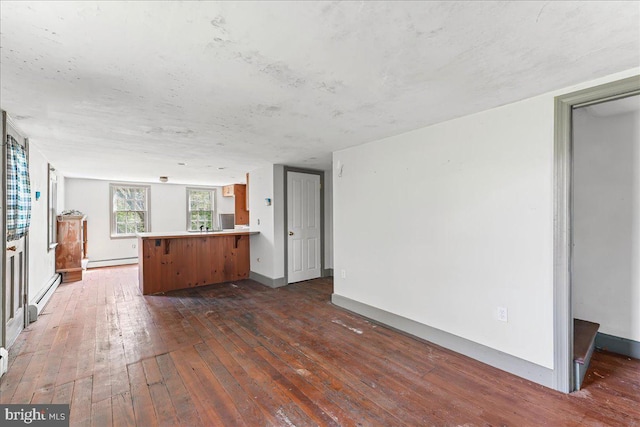 unfurnished living room featuring baseboard heating, baseboards, a baseboard radiator, and wood-type flooring