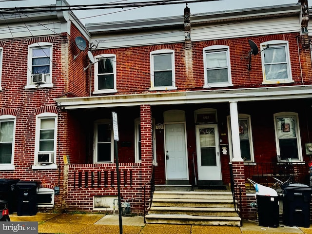 multi unit property featuring brick siding and a porch