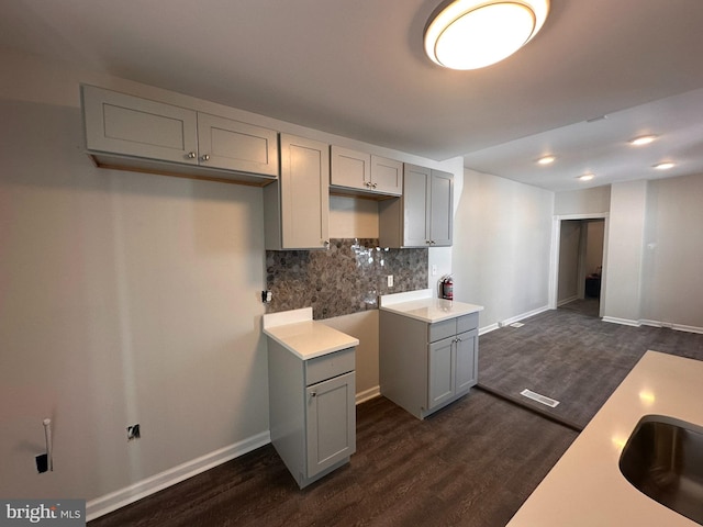 kitchen featuring visible vents, baseboards, dark wood-type flooring, backsplash, and gray cabinetry