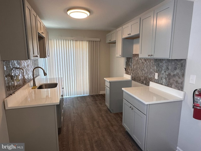 kitchen with dark wood-type flooring, a sink, light countertops, and tasteful backsplash