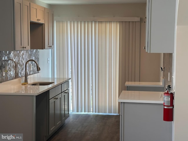 kitchen with a sink, light countertops, decorative backsplash, and gray cabinetry