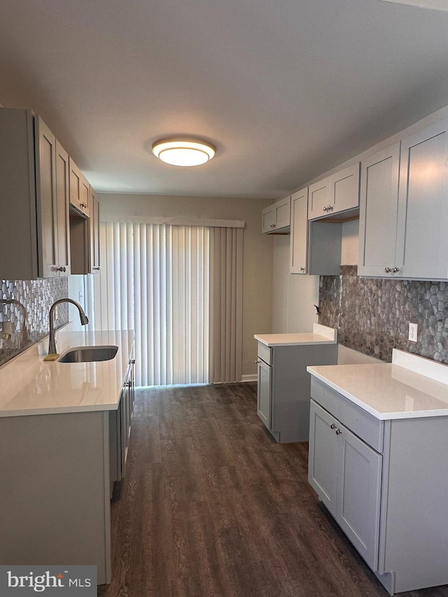 kitchen featuring dark wood-type flooring, a sink, decorative backsplash, and gray cabinetry