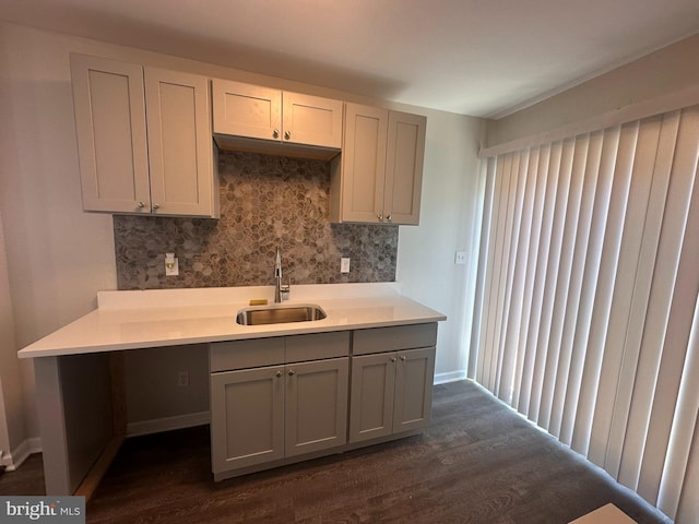 kitchen featuring decorative backsplash, dark wood-style floors, light countertops, gray cabinets, and a sink