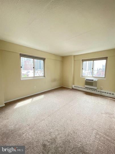 carpeted spare room with baseboards, a baseboard heating unit, and a textured ceiling