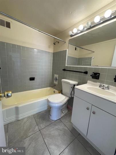 bathroom featuring vanity, tile patterned floors, toilet, shower / bathing tub combination, and tile walls