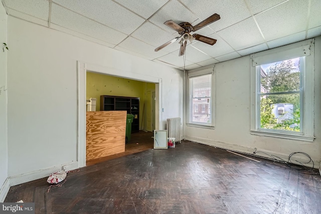 interior space with a paneled ceiling, a ceiling fan, and radiator heating unit