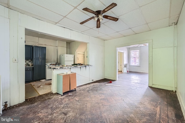 living area featuring a paneled ceiling and ceiling fan