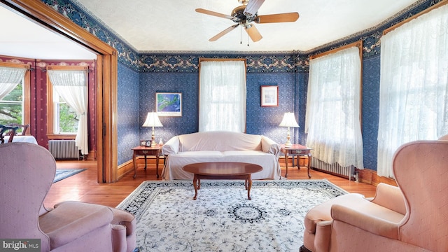 living room with radiator heating unit, wood finished floors, and wallpapered walls