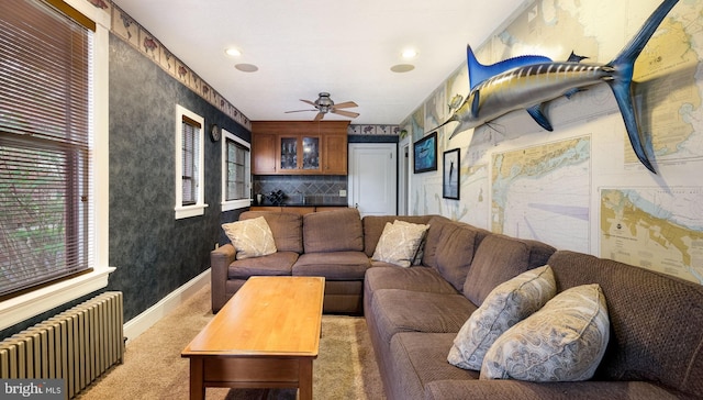living room with radiator, baseboards, carpet, wallpapered walls, and a ceiling fan