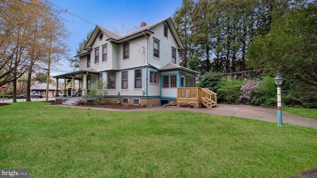 view of front of home with a front lawn, a chimney, and covered porch