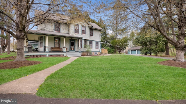 view of front of home with a detached garage, a front yard, and covered porch