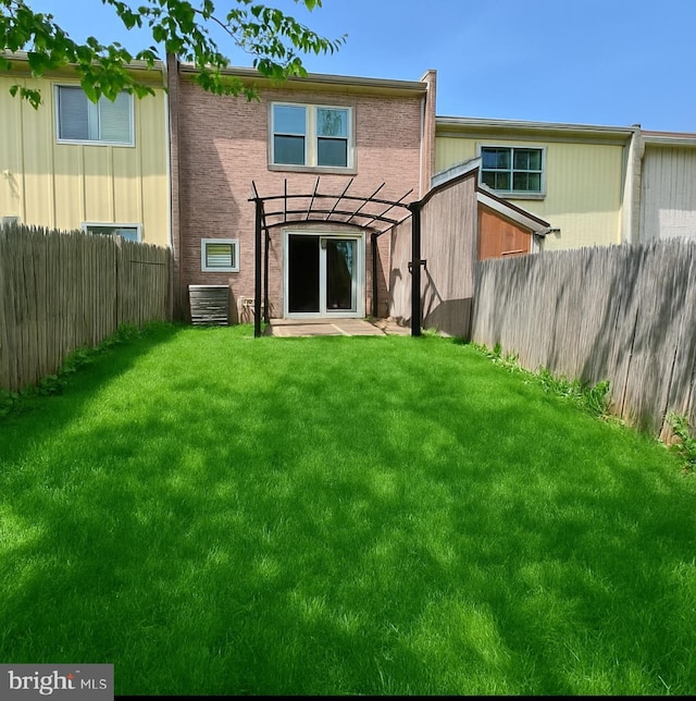 back of property with a fenced backyard and a yard