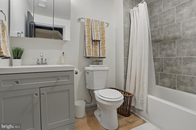 bathroom with wood finished floors, shower / bath combination with curtain, toilet, vanity, and visible vents