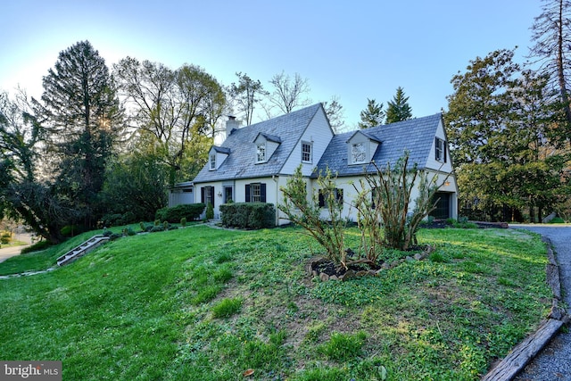 1122 Bellemore Rd, Baltimore, MD 21210 - new england style home with an attached garage, a chimney, stucco siding, a front lawn, and driveway
