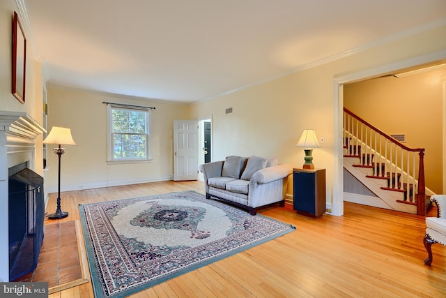 1122 Bellemore Rd, Baltimore, MD 21210 - living area featuring baseboards, light wood-style floors, a fireplace, crown molding, and stairs