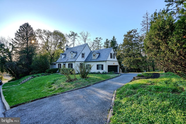 1122 Bellemore Rd, Baltimore, MD 21210 - cape cod home featuring stucco siding, a front yard, an attached garage, a chimney, and driveway