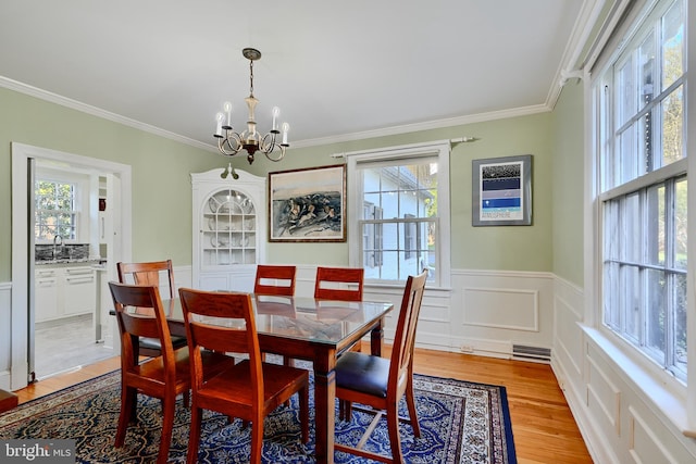 1122 Bellemore Rd, Baltimore, MD 21210 - dining space with ornamental molding, wainscoting, a notable chandelier, and light wood-style floors