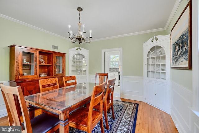 1122 Bellemore Rd, Baltimore, MD 21210 - dining space featuring an inviting chandelier, ornamental molding, visible vents, wainscoting, and light wood finished floors