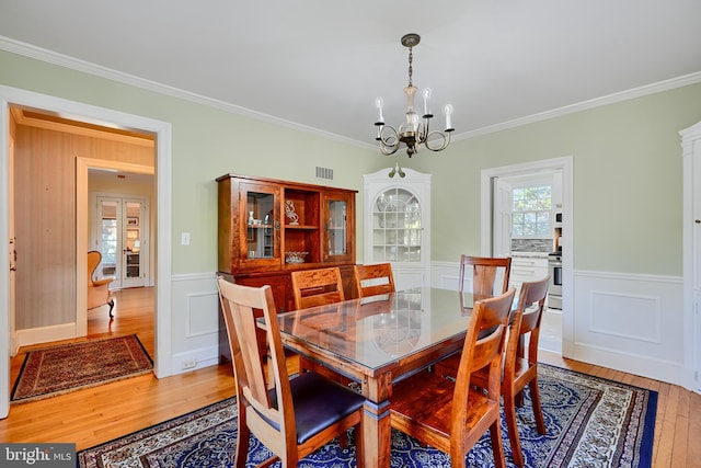 1122 Bellemore Rd, Baltimore, MD 21210 - dining space with a notable chandelier, ornamental molding, a wainscoted wall, light wood-style floors, and visible vents