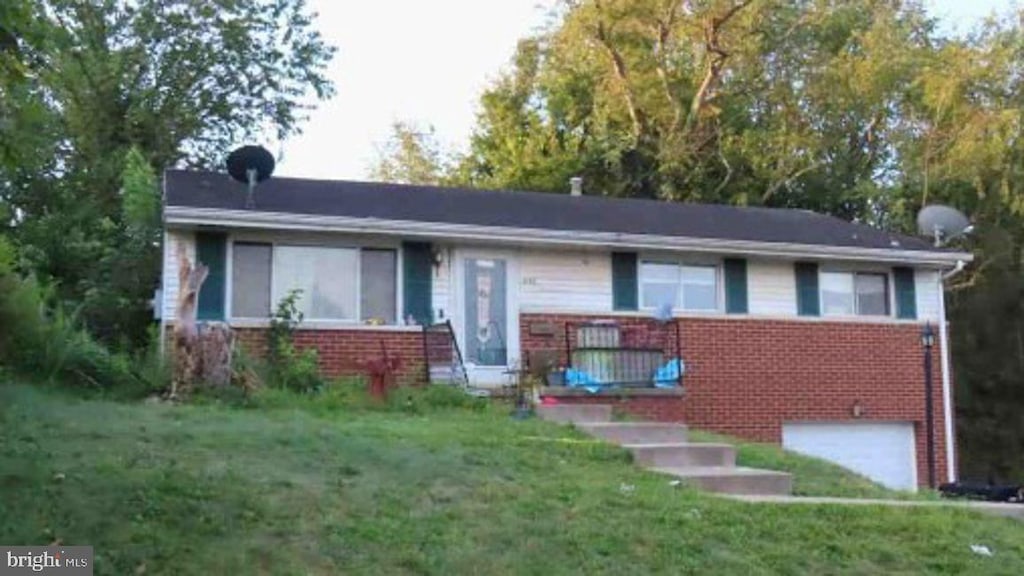 view of front of property featuring an attached garage, a front yard, and brick siding