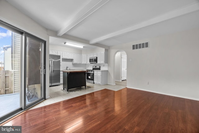 3 Bennington Pl, Newtown, PA 18940 - unfurnished living room with baseboards, light wood-style flooring, visible vents, beam ceiling, and arched walkways