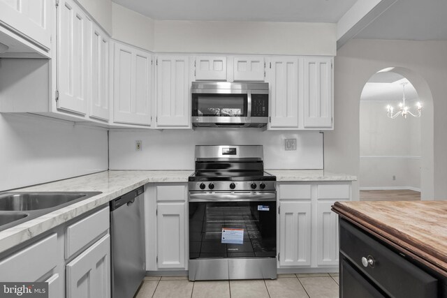3 Bennington Pl, Newtown, PA 18940 - kitchen featuring an inviting chandelier, light tile patterned floors, white cabinets, stainless steel appliances, and arched walkways