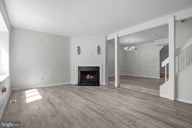 3 Bennington Pl, Newtown, PA 18940 - unfurnished living room with visible vents, an inviting chandelier, stairway, wood finished floors, and a fireplace with flush hearth