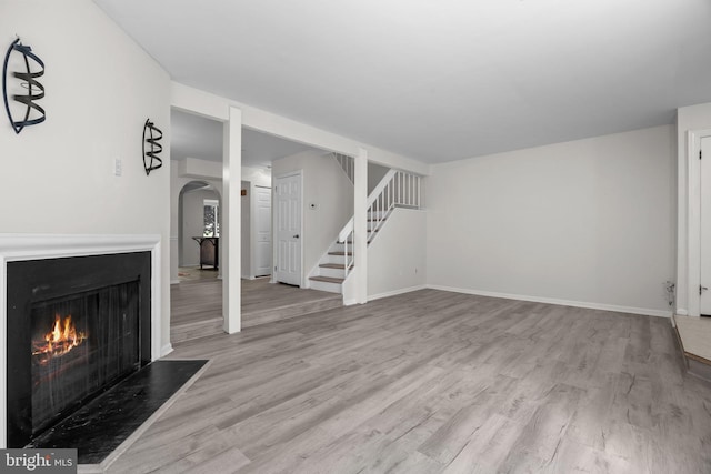 3 Bennington Pl, Newtown, PA 18940 - unfurnished living room featuring baseboards, arched walkways, a warm lit fireplace, stairway, and wood finished floors