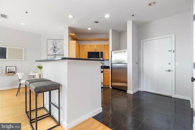 3883 Connecticut Ave NW Unit 909, Washington, DC 20008 - kitchen featuring stainless steel appliances, baseboards, a breakfast bar area, recessed lighting, and light brown cabinetry