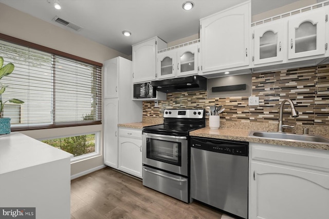 kitchen with visible vents, white cabinets, a sink, appliances with stainless steel finishes, and under cabinet range hood
