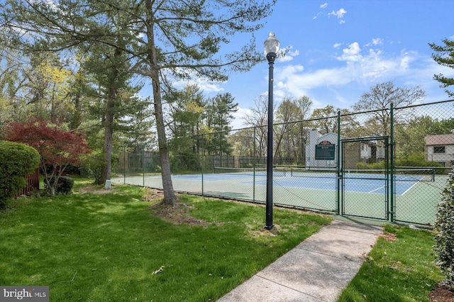 view of tennis court featuring a yard, fence, and a gate