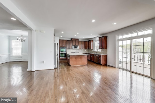kitchen with an inviting chandelier, a center island, light countertops, decorative backsplash, and stainless steel appliances