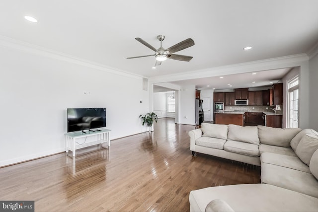 living room featuring crown molding, a ceiling fan, recessed lighting, wood finished floors, and baseboards